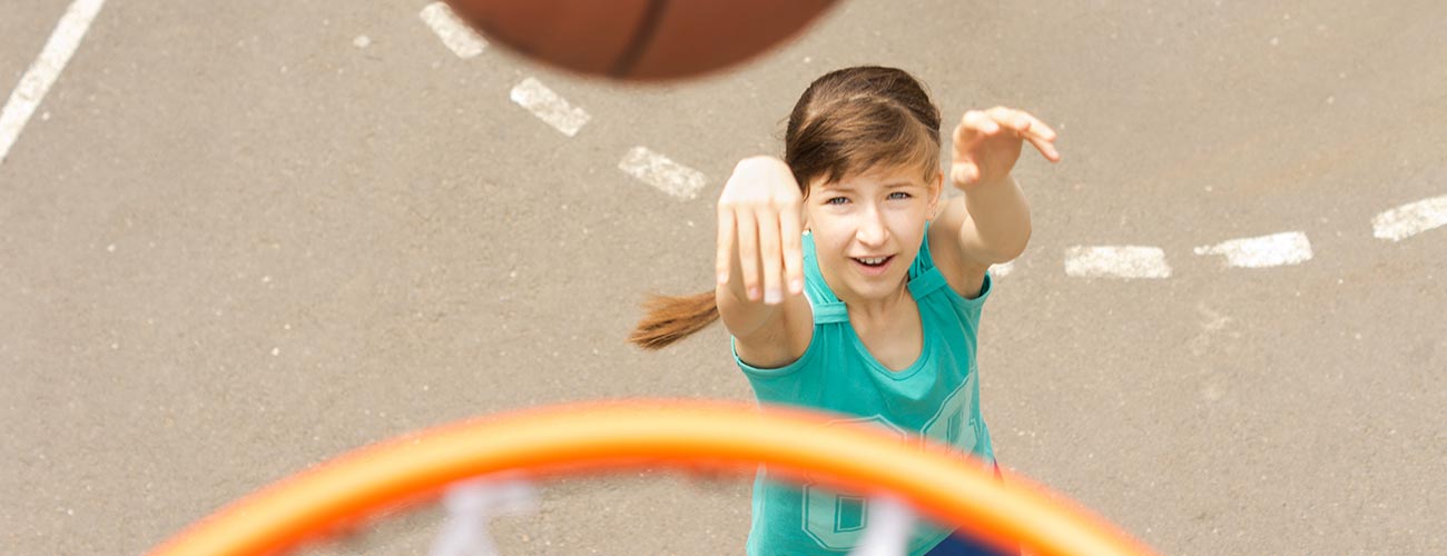 Mädchen beim Werfen eines Basketballes zum Korb: Aufnahme von oben