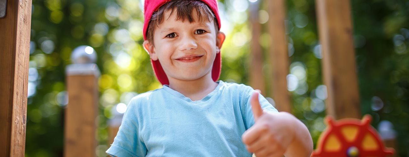 Bub mit roter Kappe zeigt den Daumen hoch