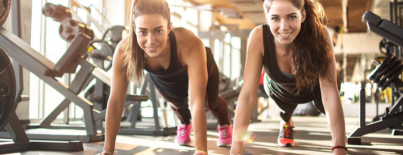 Zwei junge Frauen im Trainingsanzug beim Turnen in einem Fitnesscenter