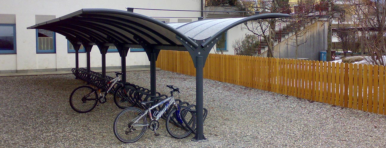 Pensiline per biciclette in un cortile di ghiaia recintato